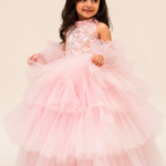 Beautiful little girl wearing a pink princess party dress with a voluminous tulle skirt and elegant pearl hairband, styled for a birthday, wedding or special occasion.